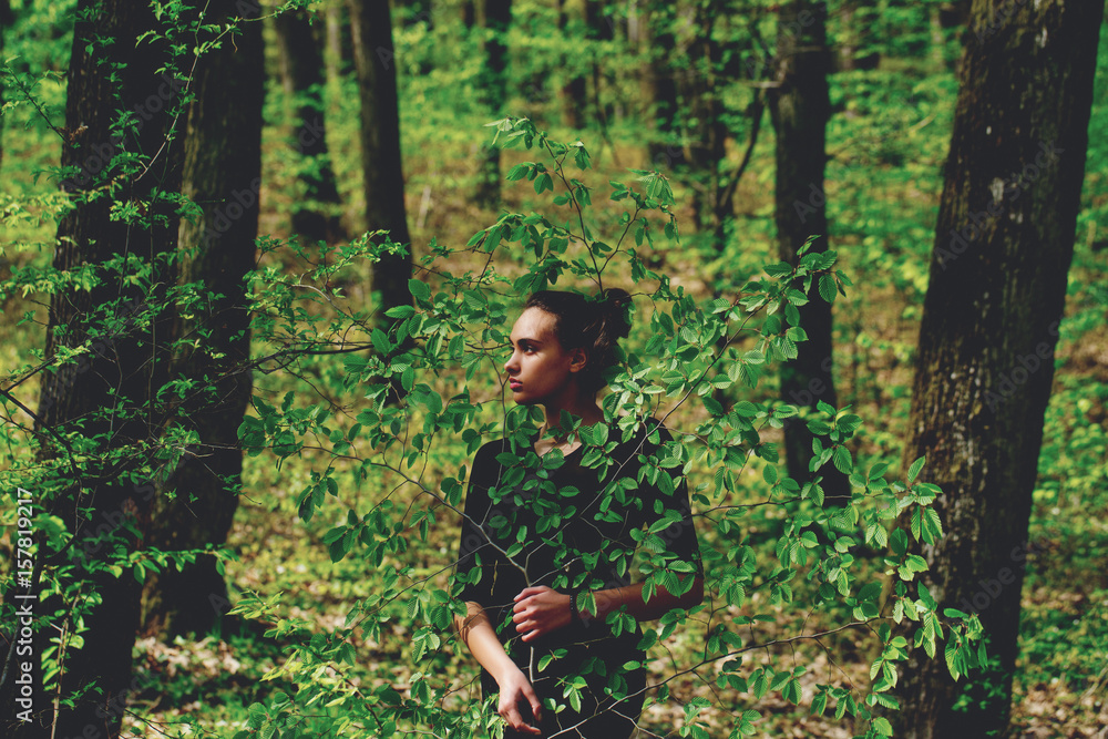 woman hiding in green tree leaves in spring forest woman hiding in green tree leaves in spring forest