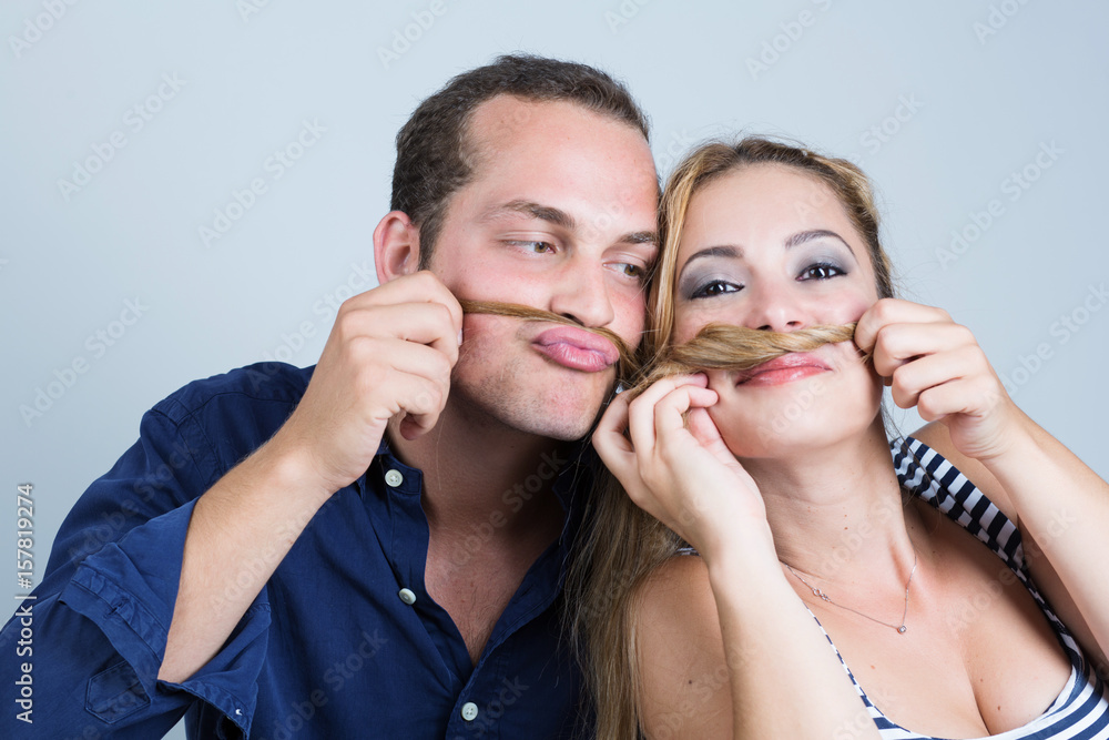 coppia di fidanzati gioca con i capelli di lei: con delle ciocche si fanno  i baffi finti Stock Photo
