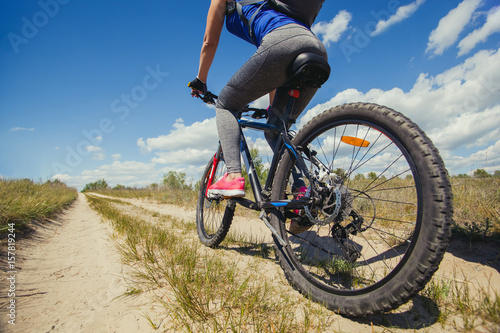 One young woman - an athlete rides on a mountain bike outside of town in a pine forest, on a summer day.