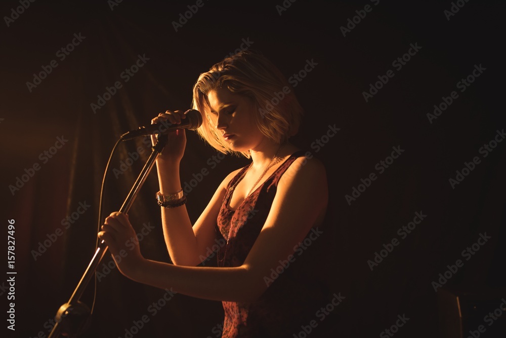 Naklejka premium Female singer holding microphone in nightclub
