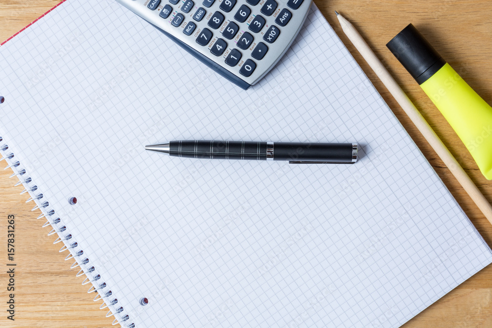 Work desk with note pad, calculator and biro on wooden table Work desk with note pad, calculator and biro on wooden table