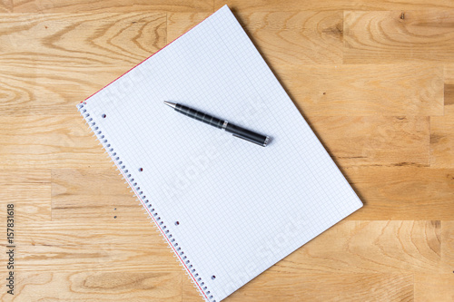 Work desk with note pad and biro on wooden table