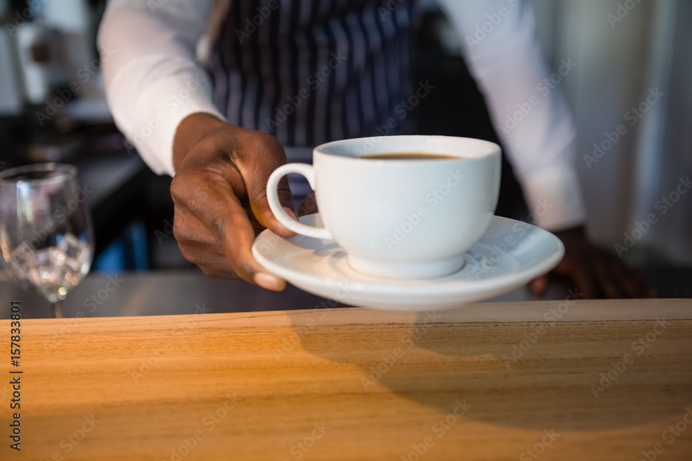 Mid section of waiter giving coffee at cafe Mid section of waiter giving coffee at cafe
