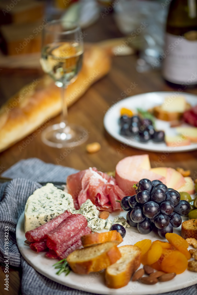 Fototapeta premium Wine and cheese platter on table with white wine.