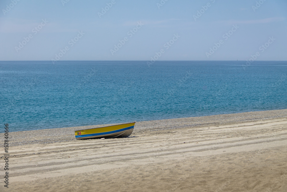 Blue and Yellow boat in a Mediterranean beach of Ionian Sea - Bova Marina, Calabria, Italy Blue and Yellow boat in a Mediterranean beach of Ionian Sea - Bova Marina, Calabria, Italy