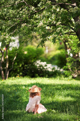 A girl in a hat is standing under a tree