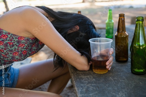 Drunken woman sleeping on the table and holding a glass of beer