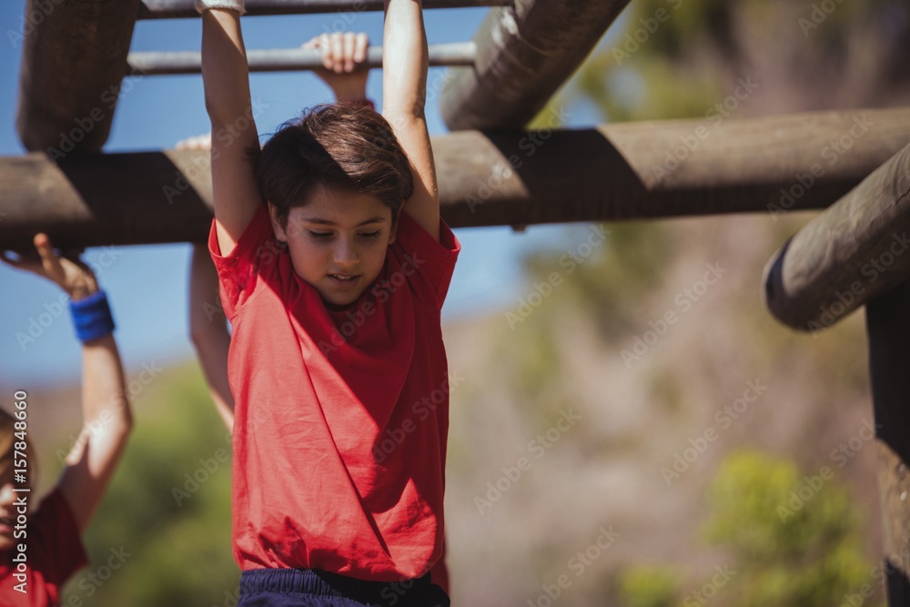 Obraz premium Kids climbing horizontal bars during obstacle course training