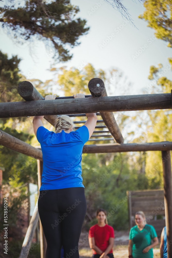 Woman climbing monkey bars during obstacle course training