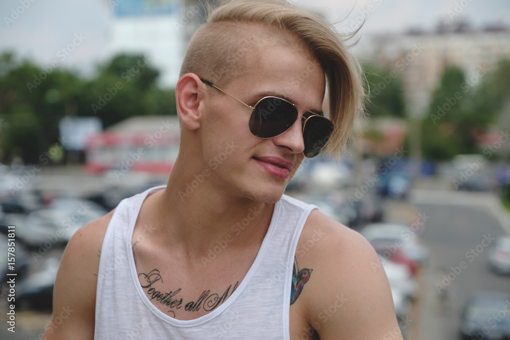 Hipster handsome man guy in stylish summer clothes in the street in sunglasses Hipster handsome man guy in stylish summer clothes in the street in sunglasses