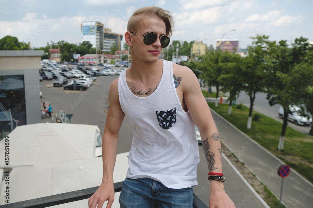 Hipster handsome man guy in stylish summer clothes in the street in sunglasses Hipster handsome man guy in stylish summer clothes in the street in sunglasses