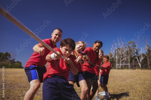 Trainer assisting kids in tug of war during obstacle 