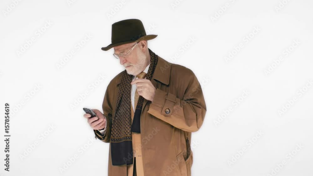 An elderly man in a hat talking on the phone on white background. He's laughing and behaving in a relaxed way An elderly man in a hat talking on the phone on white background. He's laughing and behaving in a relaxed way