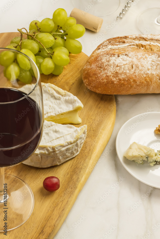 Glass of red wine with cheeses, grapes, and copy space