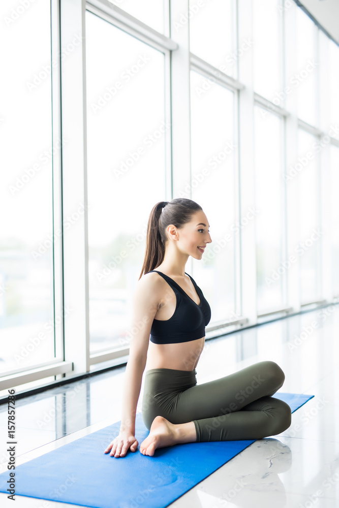 Attractive young woman sitting relax in the mat on floor after yoga training in gym Attractive young woman sitting relax in the mat on floor after yoga training in gym