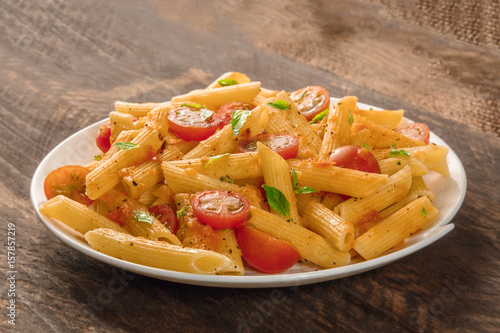 Penne pasta with tomato sauce and fresh basil leaves photo