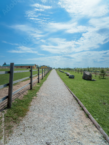 track on farm along the wooden fence on a blue sky background