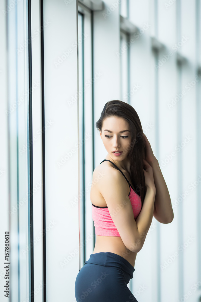 Sport girl standing in the gym at the window and possing Sport girl standing in the gym at the window and possing
