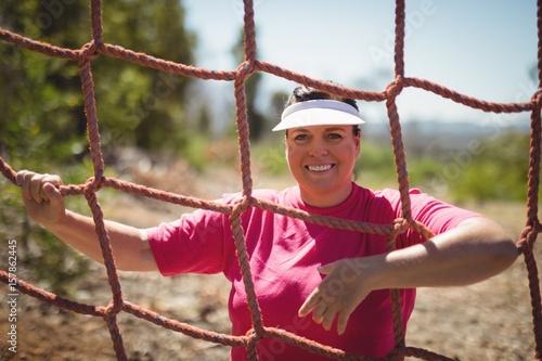 Portrait of happy woman standing near net during obstacle course