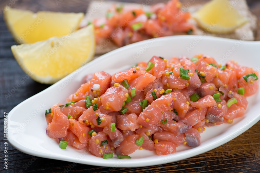 Close-up of salmon tartar served in a white plate, selective focus, shallow depth of field