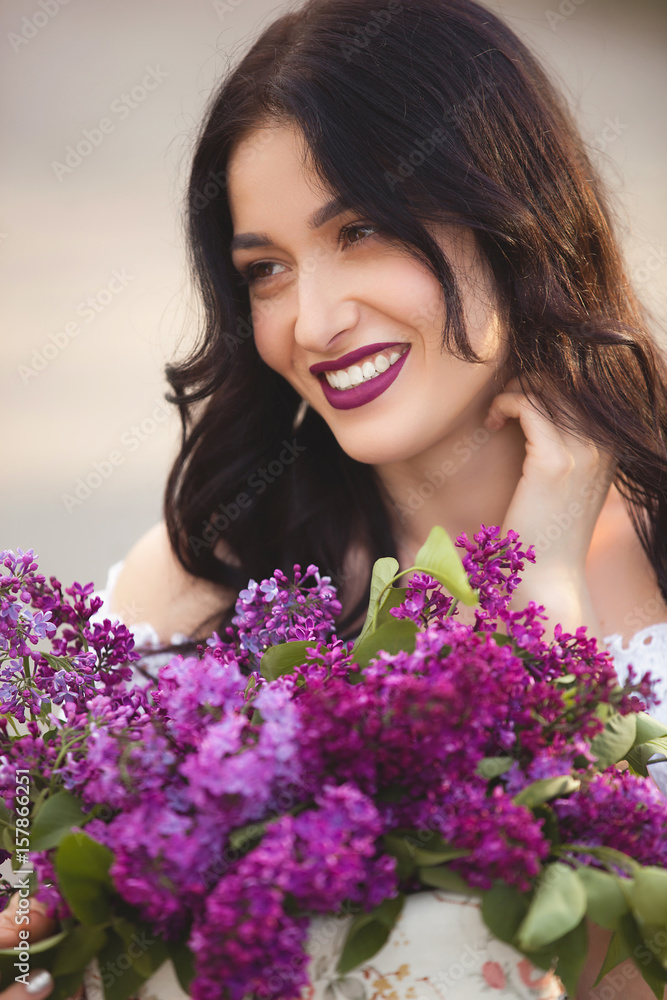 Beautiful girl outdoors. Pretty young woman with bouquet of lilac. Lady with flowers close up Beautiful girl outdoors. Pretty young woman with bouquet of lilac. Lady with flowers close up