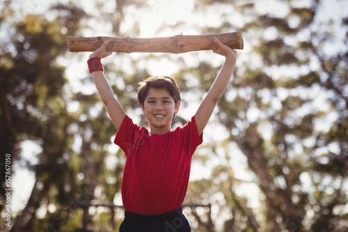 Portrait happy boy exercising with log during obstacle course