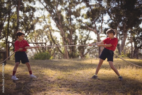 Determined kids practicing tug of war during obstacle course