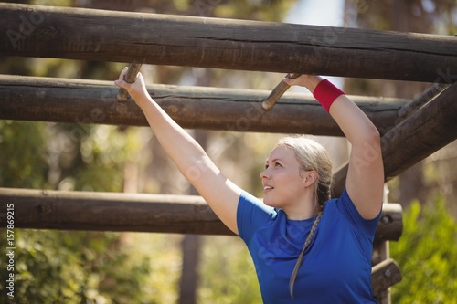 Determined woman exercising on horizontal bar during obstacle course