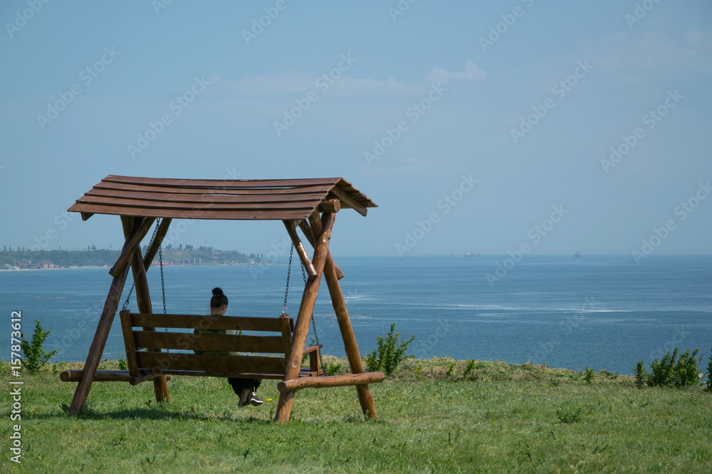 Girl sitting on a swing with a sea view