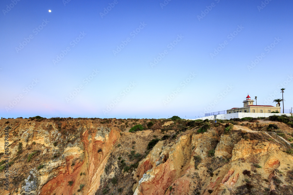 The soft colors of dawn on the lighthouse overlooking the red cliffs of Ponta da Piedade Lagos Algarve Portugal Europe