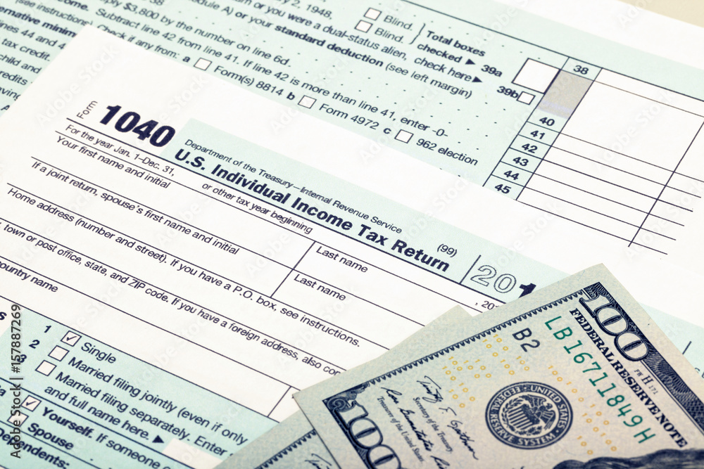 US 1040 Tax Form and dollars - studio shot. Filtered image: cross processed vintage effect. US 1040 Tax Form and dollars - studio shot. Filtered image: cross processed vintage effect.