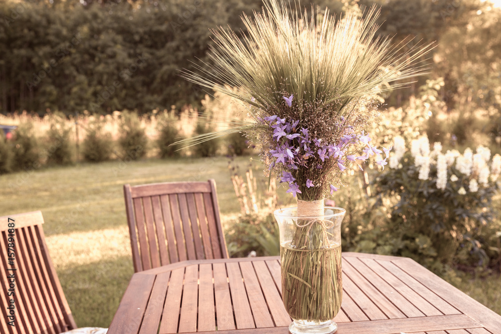 A bouqet of wildflowers on a wooden table in garden A bouqet of wildflowers on a wooden table in garden
