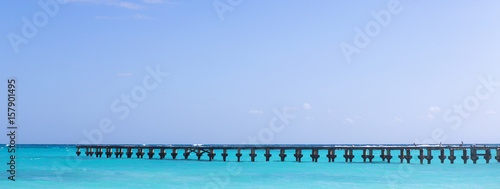 Panoramic shot of a long wooden pier in the turquoise water of the Caribbean sea. Copy space. Image fitted for banner and cover photo use.