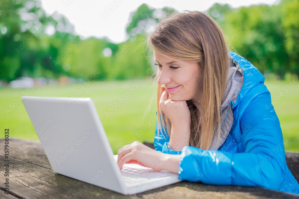 Pretty woman using laptop in park on a sunny day Pretty woman using laptop in park on a sunny day