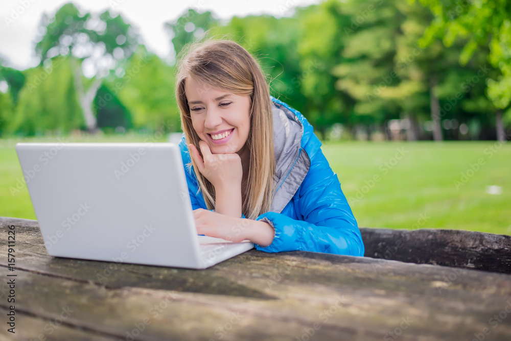 Gorgeous young brunette girl using her laptop in sunlit park. Gorgeous young brunette girl using her laptop in sunlit park.