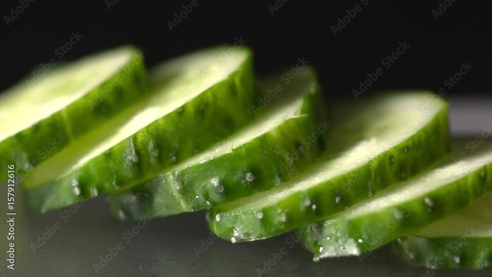 Closeup of sliced cucumber on the black background slow motion Closeup of sliced cucumber on the black background slow motion