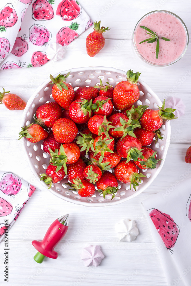 Fresh strawberries in white ceramic colander and strawberry smoothie on wooden background. Top view Fresh strawberries in white ceramic colander and strawberry smoothie on wooden background. Top view
