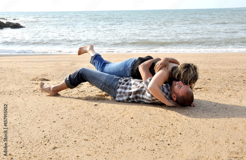 Young happy couple dating and teasing on the beach