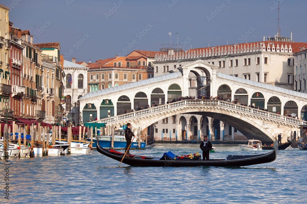 A gondola crossing the Grand Canal right in front of the Rialto Bridge, one of the most recognizable Venetian landmarks  Venice, Veneto Italy Europe