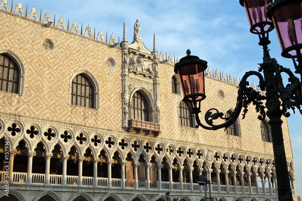 The faÃ§ade of the Doge's Palace including a lower section consisting of a ground floor colonnade beneath an open loggia. In the foreground a typical Venetian lamp post, Venice, Veneto Italy Europe