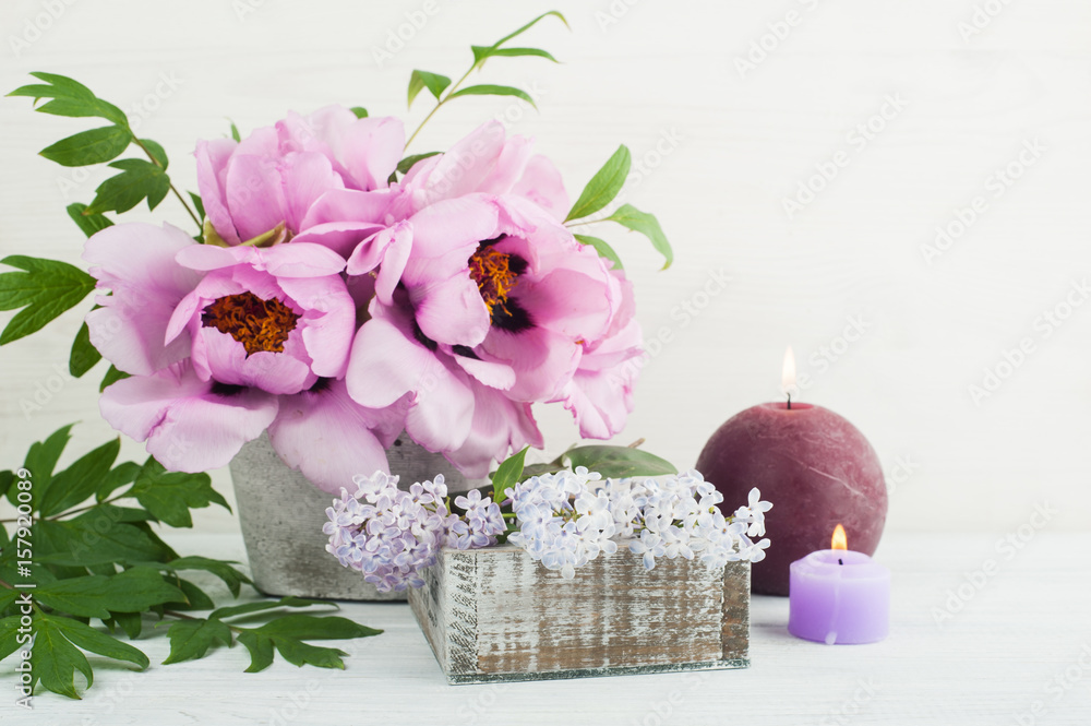 Lit candles, peonies and lilac flowers