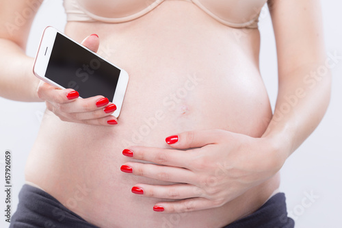 Studio portrait of pregnant woman with smartphone, baby heartbeat, isolated on white background