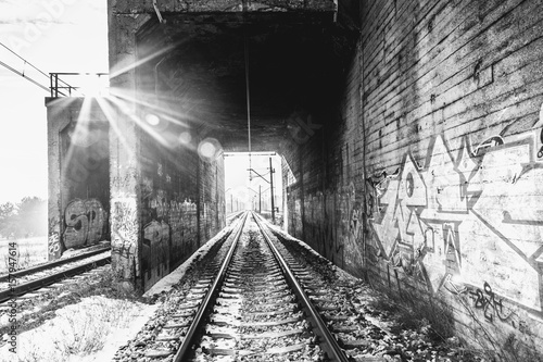 Tory kolejowe pod wiaduktem. Światło w tunelu