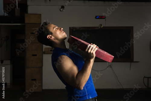 Strong man lifting a weight plate © AntonioDiaz