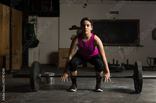 Young woman about to lift a barbell