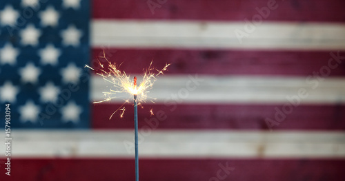 Glowing sparkler with rustic wooden flag of United States of America for independence, labor, July 4th, president, veteran and Memorial day holiday celebration background photo