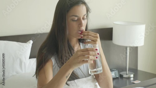 Woman taking birth control pill with glass of water