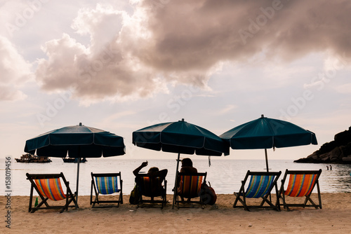 Couple on a tropical beach at island couple on island vacation holiday relax the sun on their deck chairs under a beach umbrella in thailand