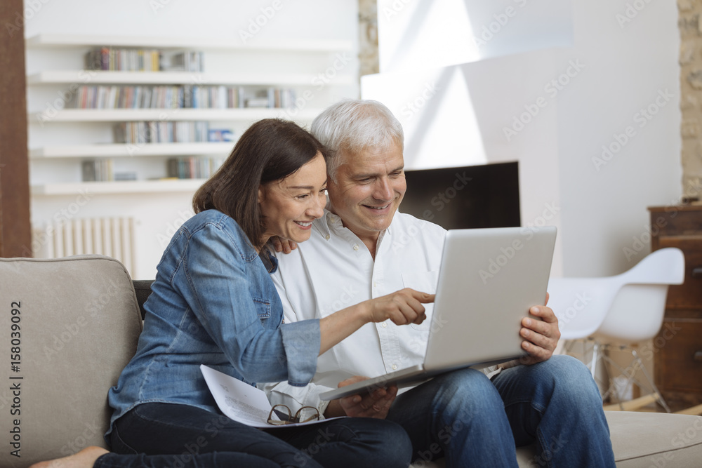 couple using their laptop to pay their bills at home in the living room couple using their laptop to pay their bills at home in the living room