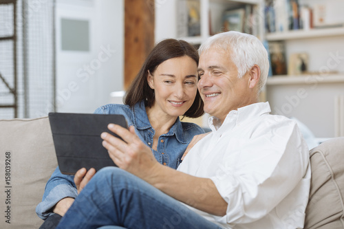 Mature couple at home websurfing with tablet